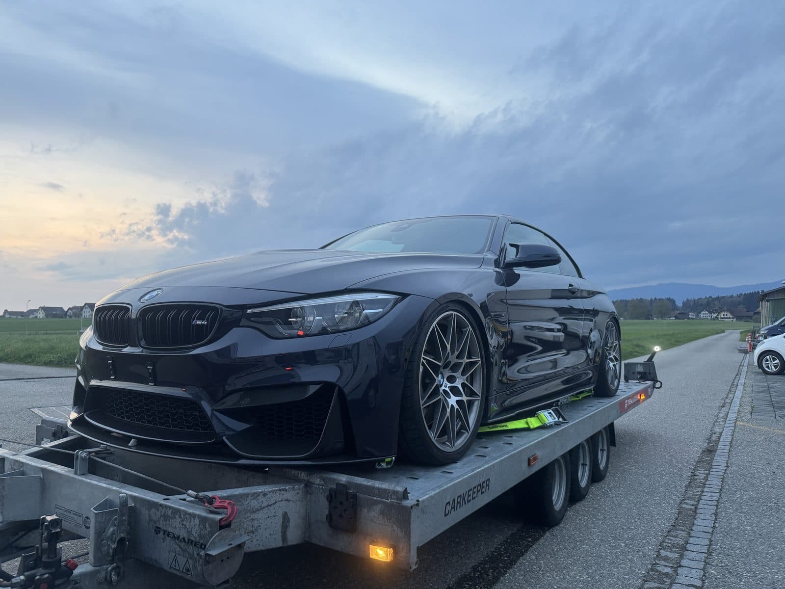 Dunkelblauer BMW-Sportwagen auf dem Anhänger in der Abenddämmerung