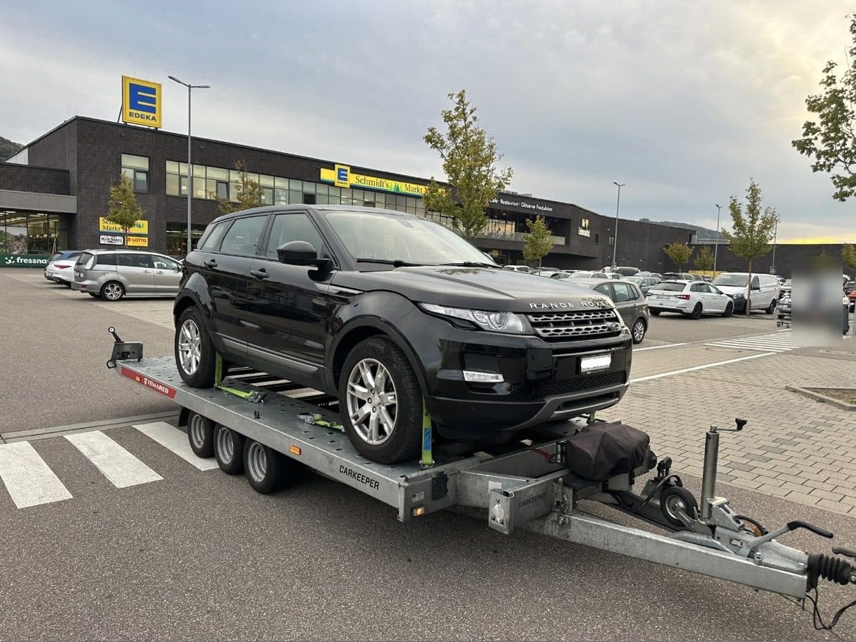 Schwarzer Range Rover auf dem Anhänger auf einem Parkplatz