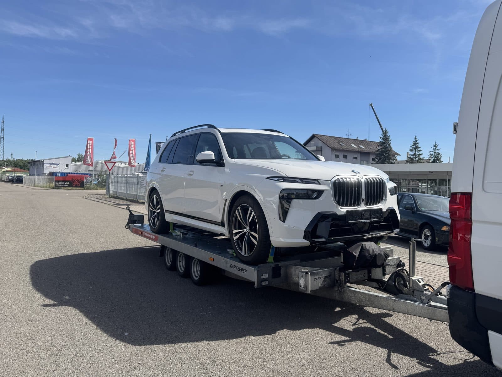 Weisser BMW-SUV auf dem Anhänger hinter dem Transportfahrzeug